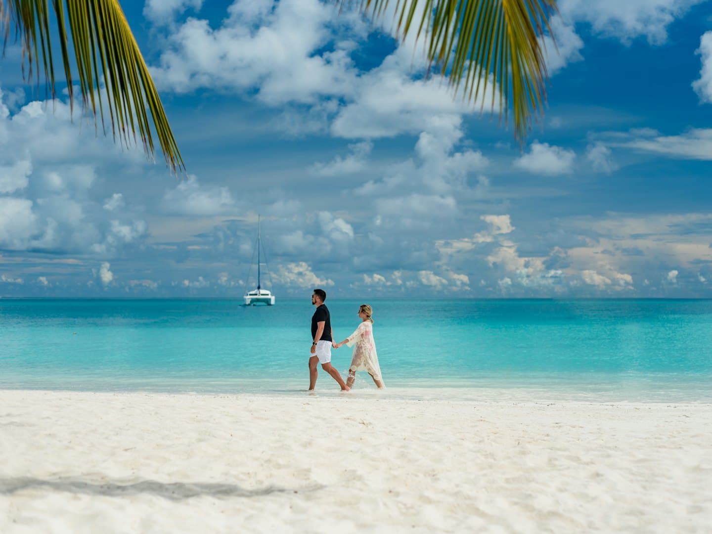 Two people walking on a white sand beach