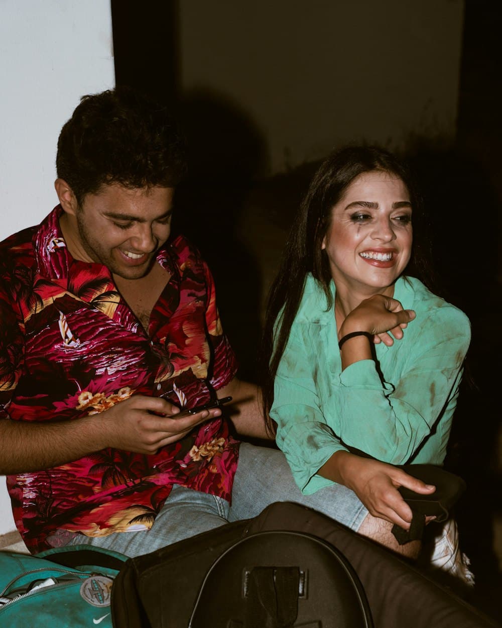 A couple smiling while planning a trip on a phone