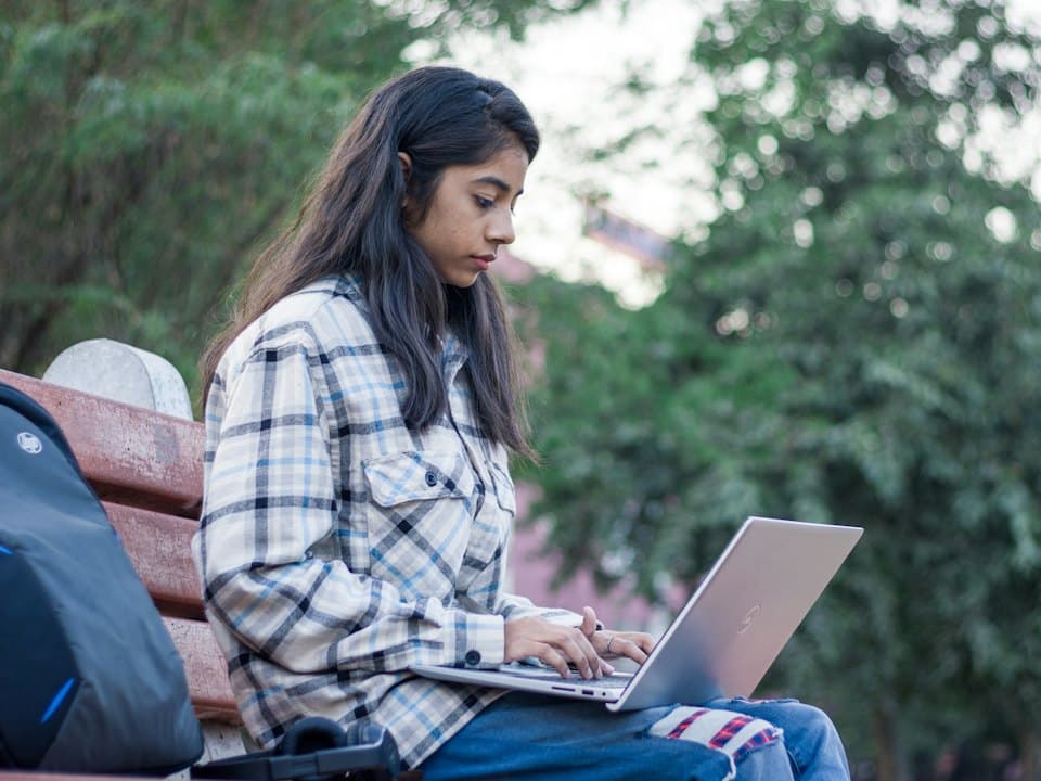 A student working on her laptop outdoors