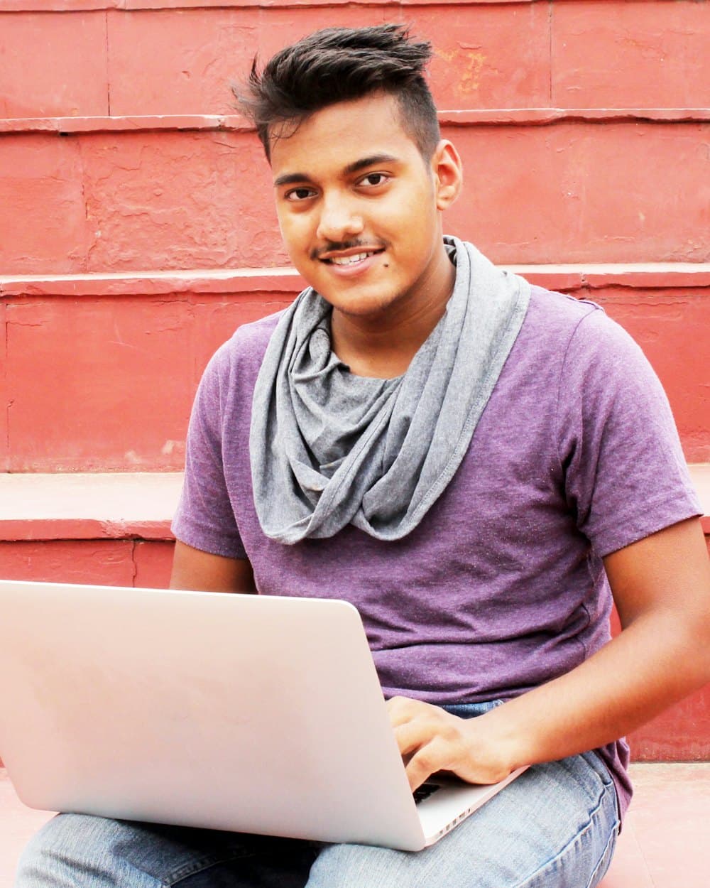 A smiling young man working on his laptop
