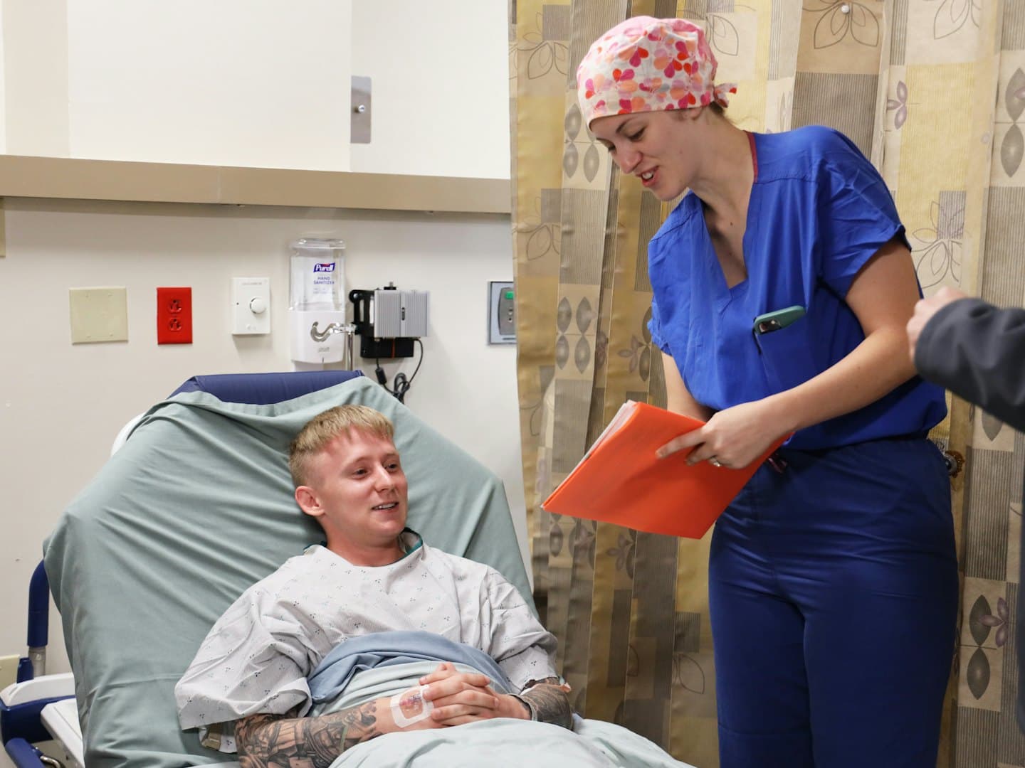A nurse talking with a patient in a hospital bed