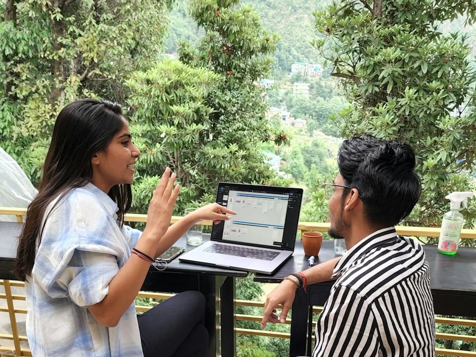 Two people talking over a laptop outdoors
