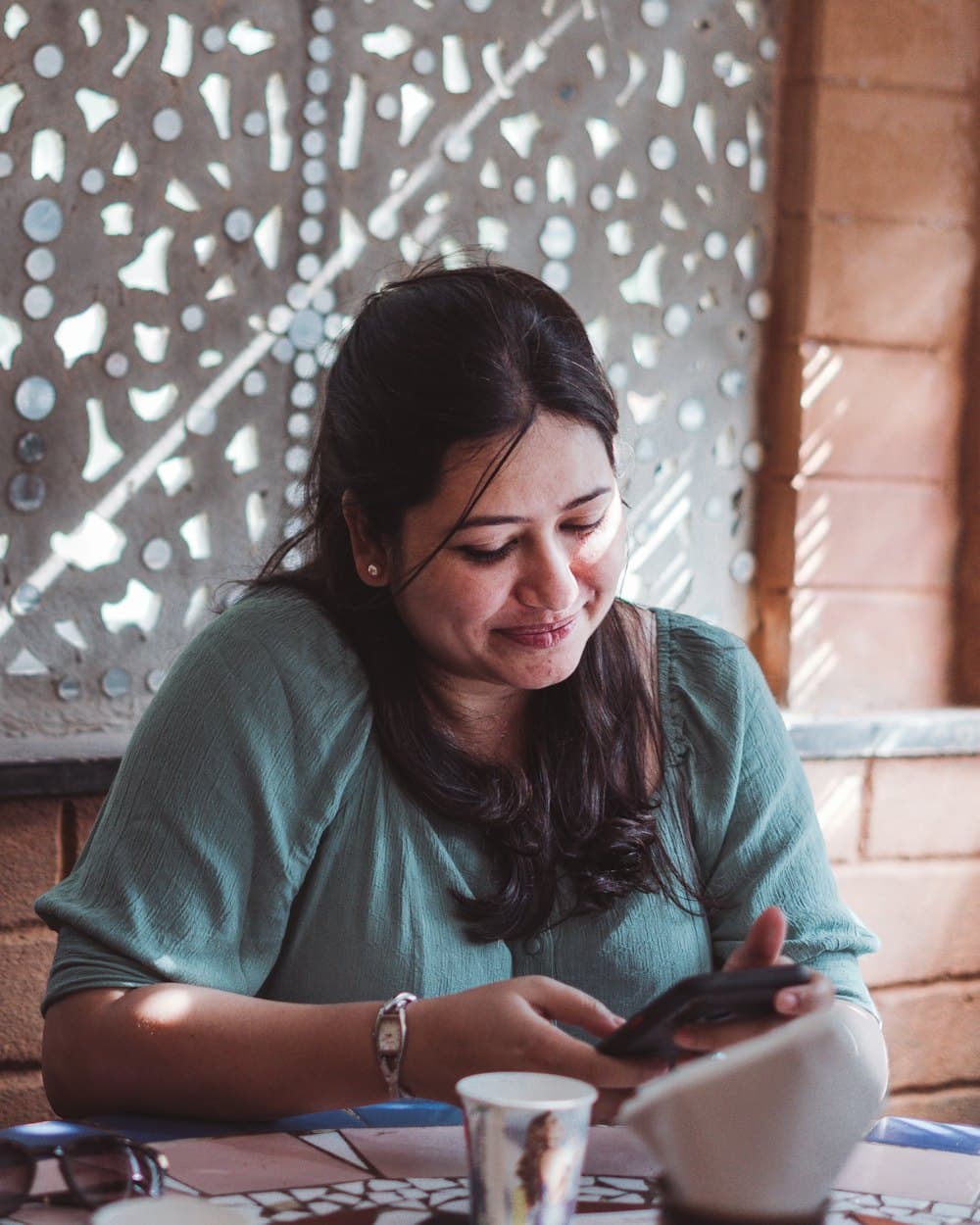 A woman smiling at her phone in a café